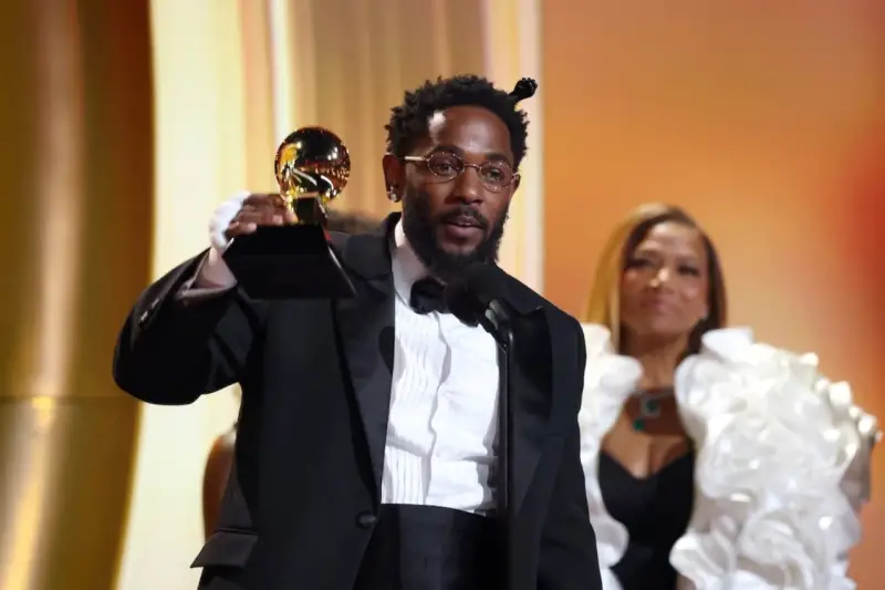 Artysta w garniturze odbiera nagrodę Grammy: najlepsza piosenka - rap.