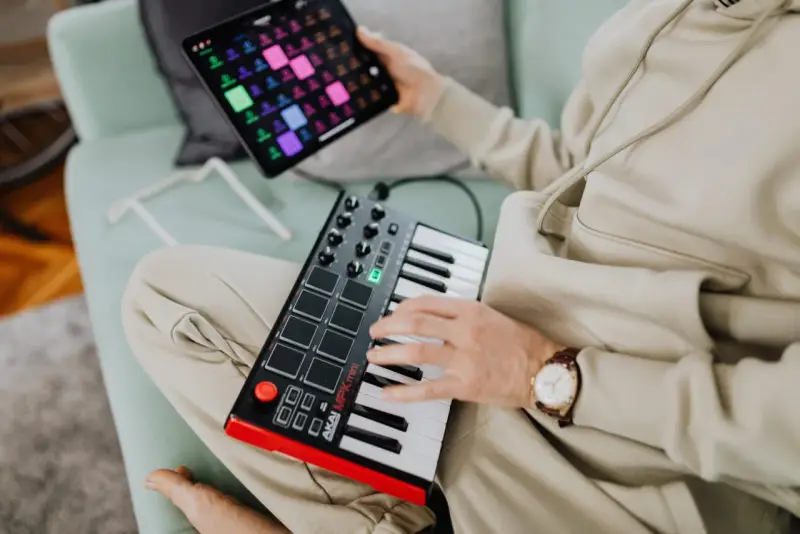 Osoba tworzy muzykę na kontrolerze midi usb. To świetny sposób na rozpoczęcie przygody z produkcją muzyczną.